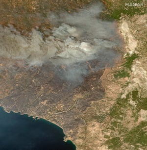 Smoke hangs in the air over a mostly brown and tan coloured landscape.