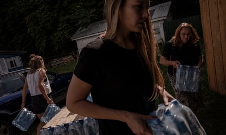 People carrying packs of water bottles