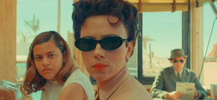 Grace Edwards, with shoulder-length hair, and Scarlett Johansson in sunglasses in a scene from Asteroid City with a man in a hat and sunglasses seated behind them