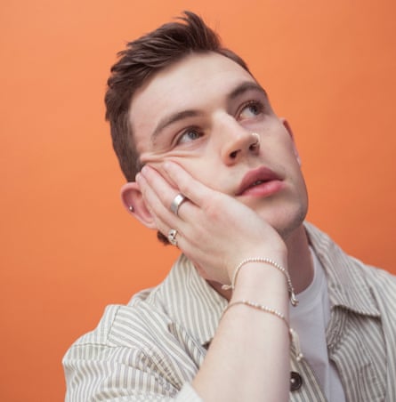 Head shot of Chris D’Arcy, against orange background, for a feature on five generations of gay men