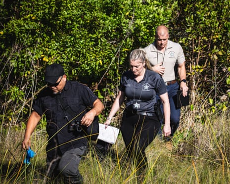 law enforcement agents walk outside in a grassy area