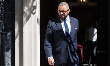 James Cleverly in doorway in suit holding red folder