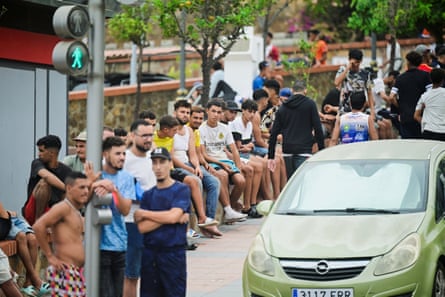 Crowds sitting on a wall on the side of a road