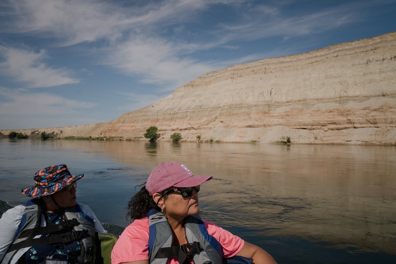 Two women in a boat on a river, looking at mountains
