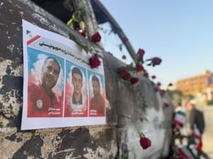 red roses on a bombed out car with a printout with three men's faces on it