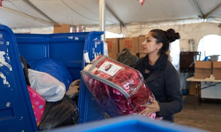 Fareeha Haq places donations in a large blue donation bin.