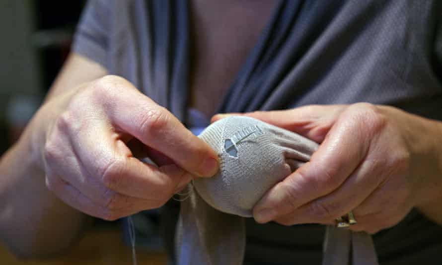 A person darning a sock with a darning mushroom