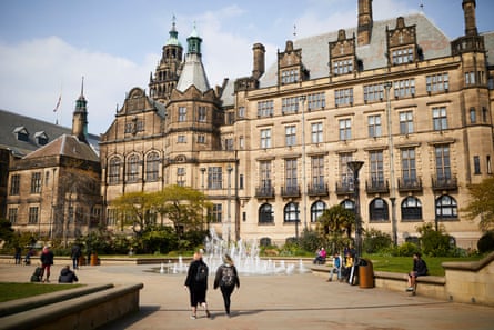 People walk near a fountain in Sheffield’s Peace Gardens, in front of the town hall