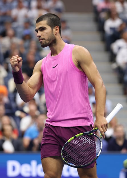 Alcaraz with fist raised in triumph, the other hand holding a racket before spectators