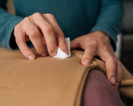 A man spot cleaning a fabric with a cleaning cloth