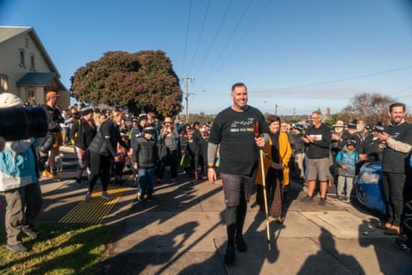 A man in a black shirt walks amid a crowd.