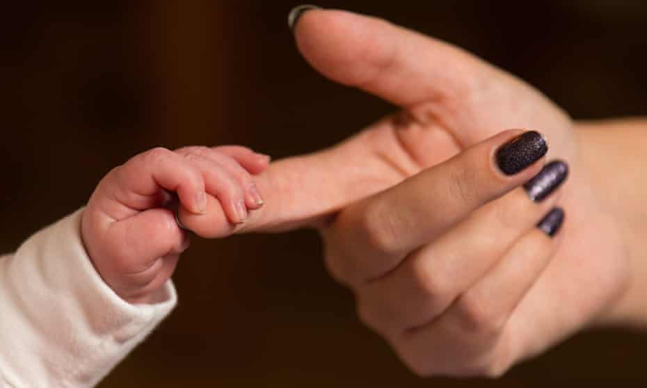 Baby holds an adult’s finger.