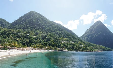 Two conical volcanic peaks, heavily forested, by a white beach