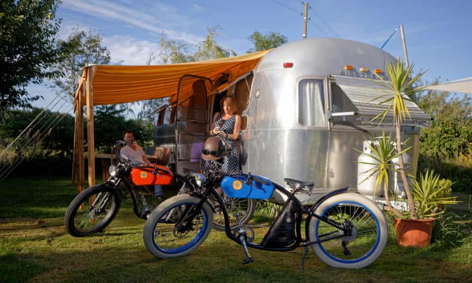 Two people outside and Airstream caravan with bikes in the foreground at Airstream Europe trailer park in France.
