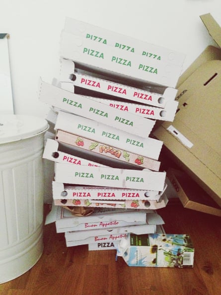 The wood floor of an apartment is stacked high with a tottering pile of empty pizza boxes.