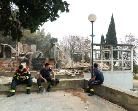 Firefighters rest next to a burnt-out house following wildfire in Mala Luka, Croatia.