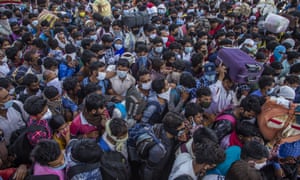 Crowds try to board buses out of the capital, Delhi.