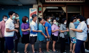 A Thai official distributes queue tickets to people standing in line to buy face masks outside a pharmacy in Bangkok, Thailand, 04 March 2020. Thailand is facing a shortage of masks and hand sanitizers as people have been panic buying these items over fear of a coronavirus outbreak in the country.