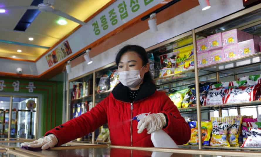 An employee of a North Korean general store disinfects the worktops