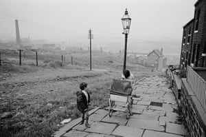 Bradford, 1970. Pushing a pram up an unadopted road