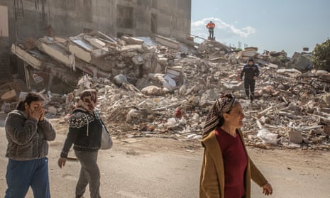 People walk past a ruined building in Samandağ, Turkey