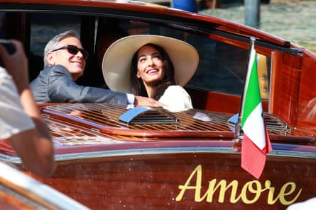 George Clooney and Amal Clooney looking up from a boat.