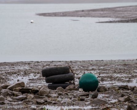 Stacked tyres and a green buoy lie on the rocky shore of Ardingly reservoir