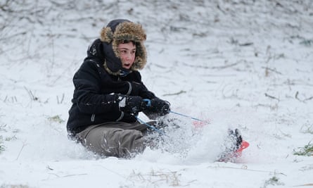 A boy goes sledging down a hill in the snow