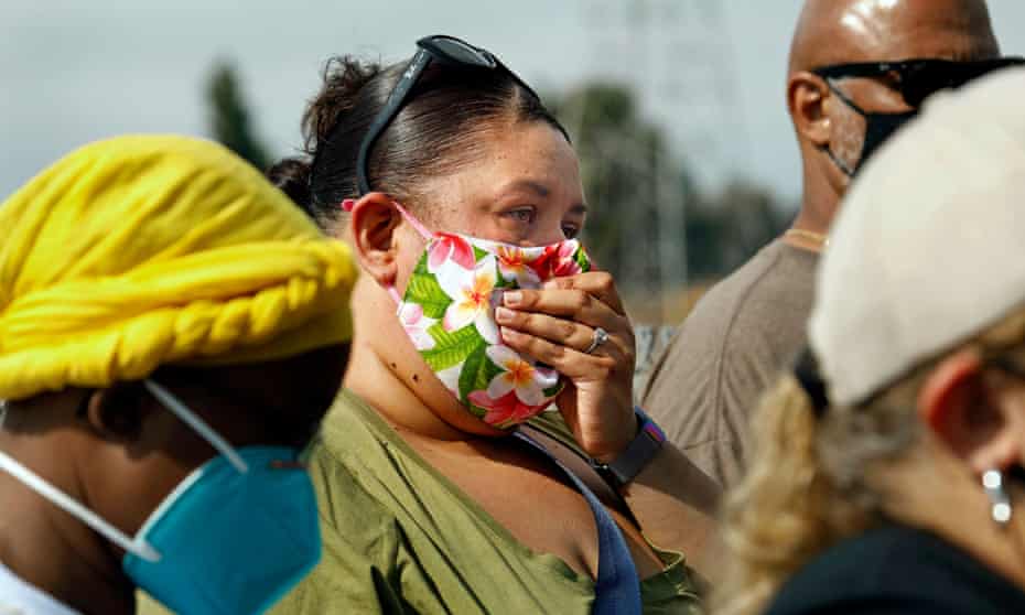 A woman holds her nose over her face mask as Carson residents gather during a press conference regarding the smell on 22 October.