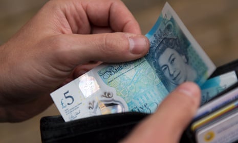 A person taking a £5 note out of a wallet