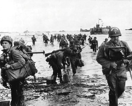 A black-and-white image of soldiers making their way through shallow water on to a beach