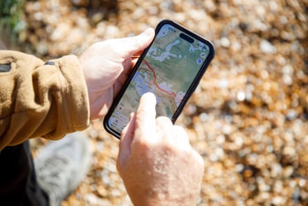 Close-up of Bushby’s hands looking at a phone with a map and a path