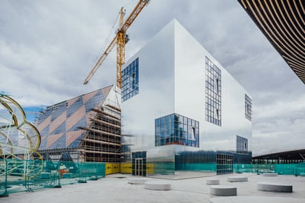 Mirror-polish … Barozzi Veiga’s completed building, with 6a’s chequerboard design alongside, and the ‘caterpillar’ food hall by SelgasCano taking shape left.