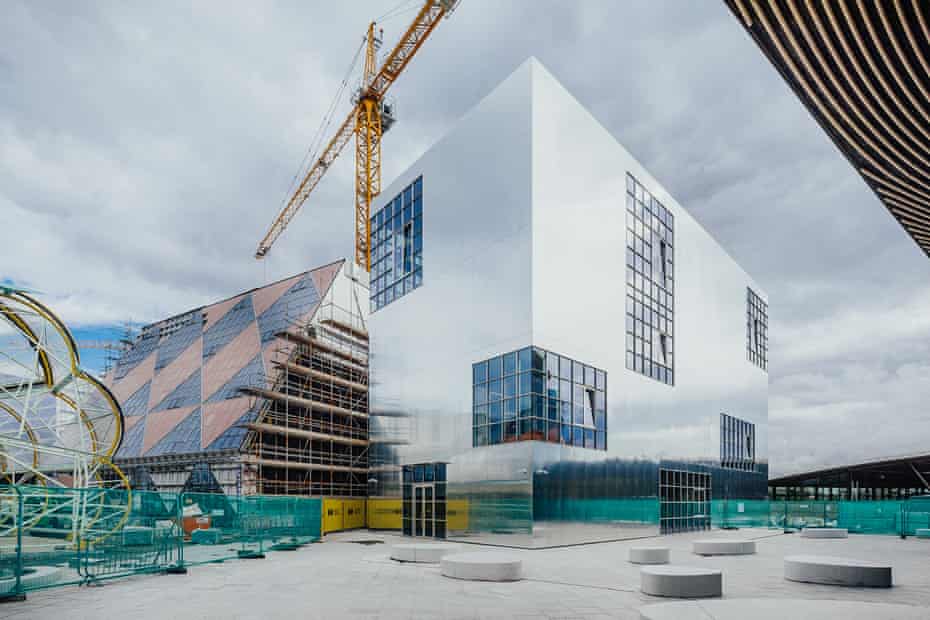 Mirror-polish … Barozzi Veiga’s completed building, with 6a’s chequerboard design alongside, and the ‘caterpillar’ food hall by SelgasCano taking shape left.