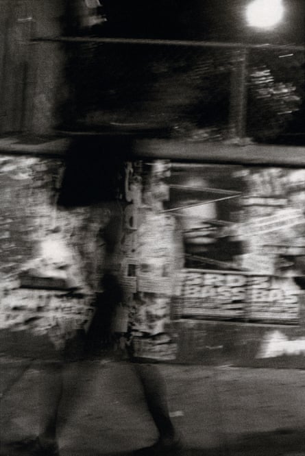 blurry black and white image of person in front of wall covered in flyers and ads