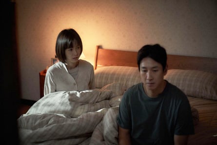 A man and woman sitting by a bed
