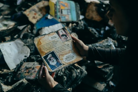 A person hold's the remains of a picturebook with the charred remains of other children's books on the floor