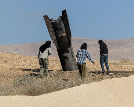 People stand next to part of a missile protruding from the ground, following strikes from Iran, in the central West Bank, 8 June, 2026.