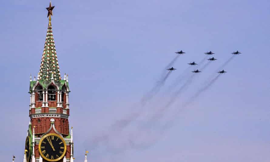 Eight jet fighters with smoke trails; ornate clock tower to left of picture