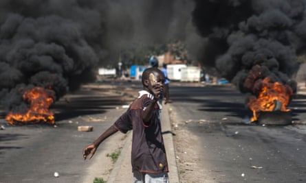 A protester throws rocks next to burning tyres during a demonstration against President Robert Mugabe.