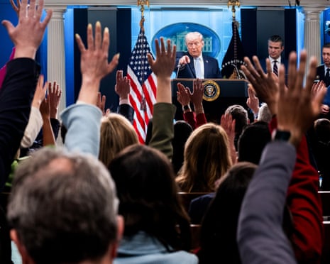 an older man at a lectern points to a crowd with their hands raised