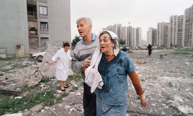 A wounded woman is helped to get out of her apartment building after it was hit by a rocket fired from Bosnia Serb positions, June 1995.