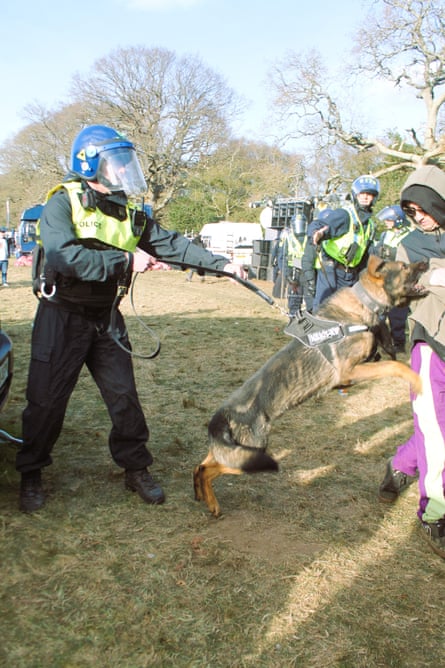 A police dog, held back by a police officers lunges towards ravers.