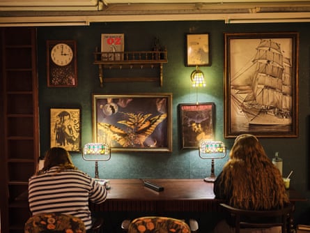 Two students studying at a table below portraits with bright lamps
