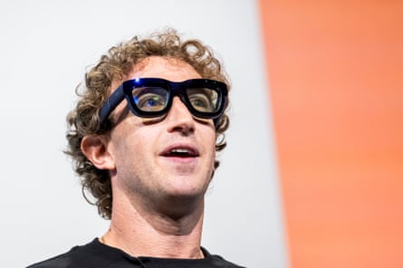 Mark Zuckerberg wears thick-rimmed glasses that has a small light emanating from them