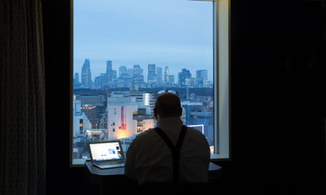 A man on a laptop looking out of a window at a cityscape