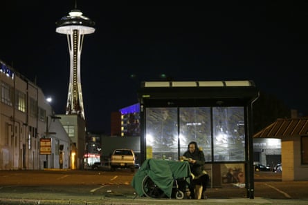 Dave Chung, who says he has been homeless for five years, eats a meal before bedding down in a bus shelter in view of the Space Needle in Seattle.