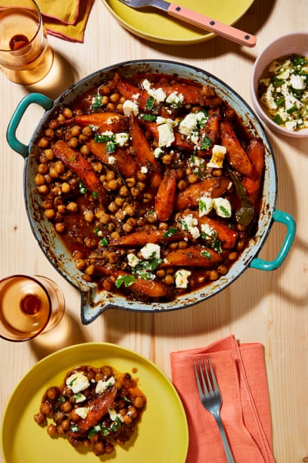 Un castron mare cu un tajine de năut, roșii și morcovi, acoperit cu brânză feta și presărat cu ierburi.