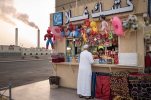 A roadside shop with the chimneys of a water desalination plant rising in the background