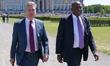 Keir Starmer walks with shadow foreign secretary David Lammy along a gravel path with a large building in the background
